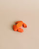 A small, orange crab from the Handmade Holzwald Underwater World Set rests on a beige surface—showcasing handmade wooden sea animals ideal for educational wooden toy collections.