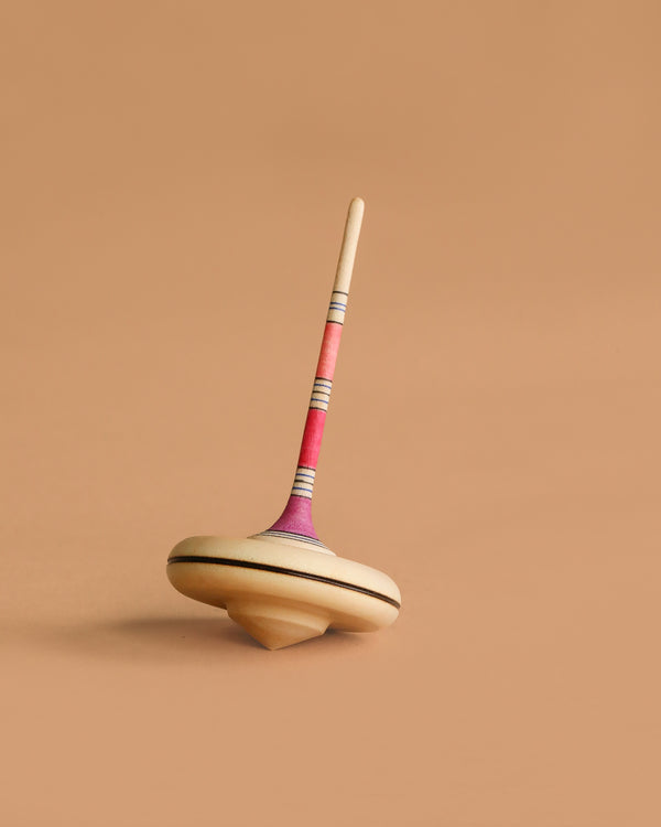 The Mader Spaghetti Spinning Top - Purple is crafted from durable Maple wood with a safe, easy-to-grip stick, ensuring hours of fun play while meeting toy safety standards.