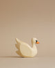 A Handmade Holzwald Swan figurine with a smooth finish and a small black and orange detail on the beak, made from sustainable toys materials, placed against a plain beige background.