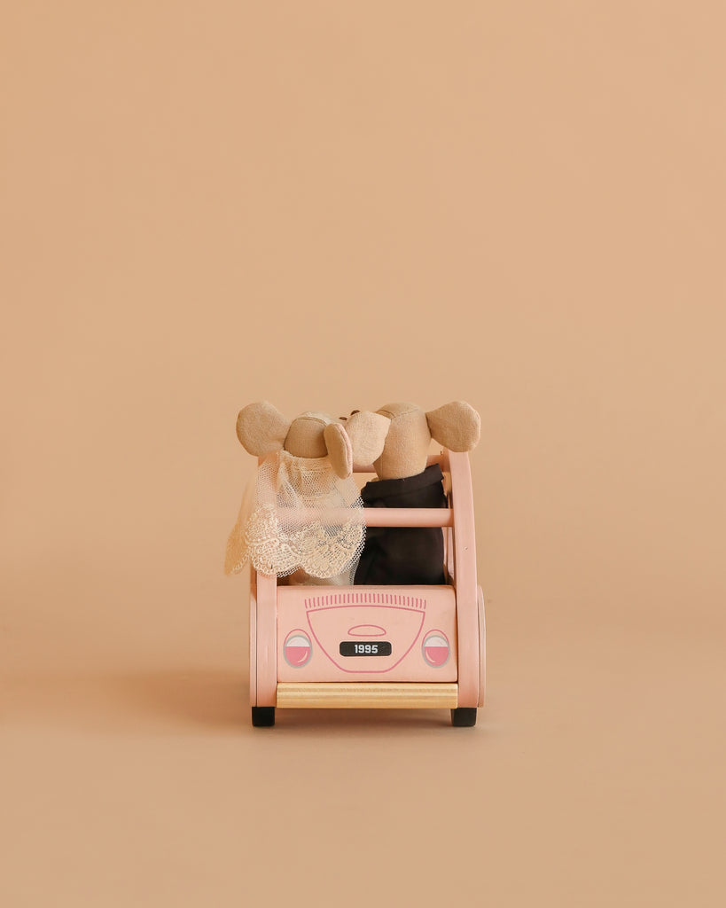 Two Maileg Just Married Set mice sit in a pink toy car—one wears a lace veil, evoking a wedding scene. The beige background and "1995" license plate add classic Sophie's Dolls House charm.