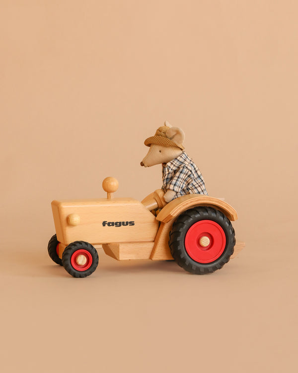 The Maileg x Fagus Tractor Set features Granddad Mouse in a plaid shirt and hat riding a handcrafted wooden tractor with red wheels, set against a beige background—a delightful showcase of classic toy charm.