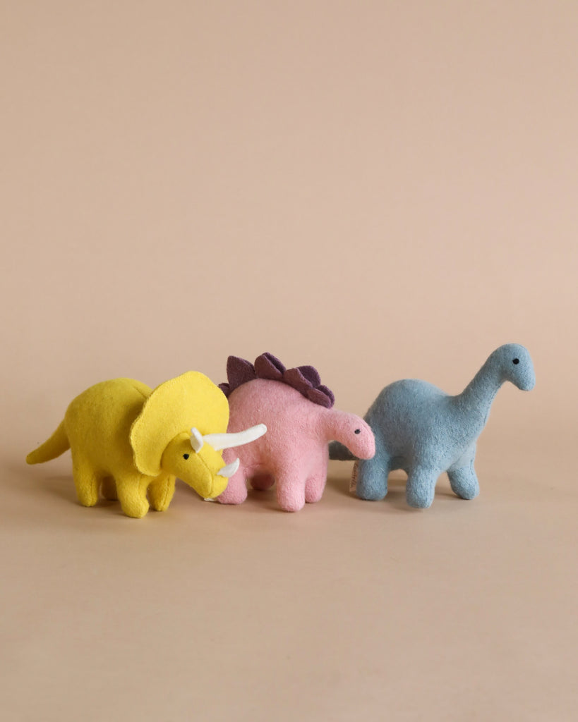 three stuffed dinosaur toys standing.