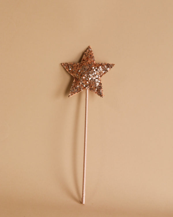 A single Magic Wand - Pink Sequin Star from Luciole et Petit Pois on a beige background. The wand has a long, thin handle and a star-shaped, sequin-covered top. The elegant piece is centered in the image against the plain, neutral backdrop.