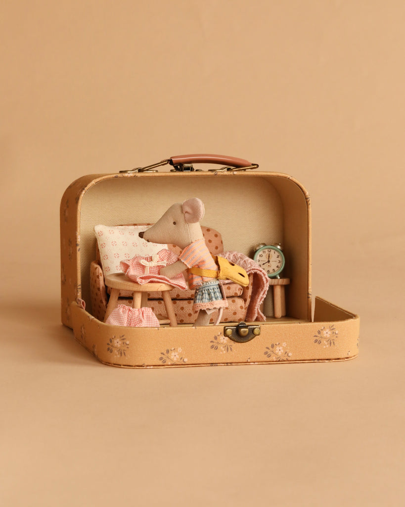 The Maileg On The Go Suitcase Set features a Little Sister Mouse in charming clothes inside an open beige suitcase styled as a cozy room with a chair, table, pillow, and alarm clock—perfect for your Maileg Dollhouse Accessories collection.