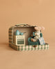 The Maileg On The Go Suitcase Set features a Big Brother mouse relaxing in a plaid armchair with a tiny stove, kettle, and pot—all arranged in an open suitcase for a cozy, room-like scene against a warm beige backdrop.