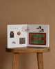 The Sports Storytime Set is shown open on a wooden stool, featuring illustrations of basketball gear—a jersey, ball, hoop, scoreboard, sneakers, whistle, and court—set against a plain beige background.