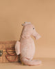 The Senger Naturwelt Cuddly Animal - Seahorse in light pink sits upright beside a closed wicker basket with handles, set against a plain beige background.