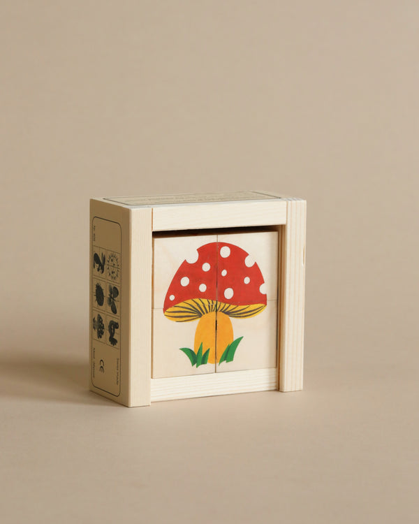 A Wooden Block Puzzle - 4 Piece Woodland made of sustainably harvested wood with Japanese characters on the side, displaying a vibrant illustration of a red mushroom with white spots on its front pane.