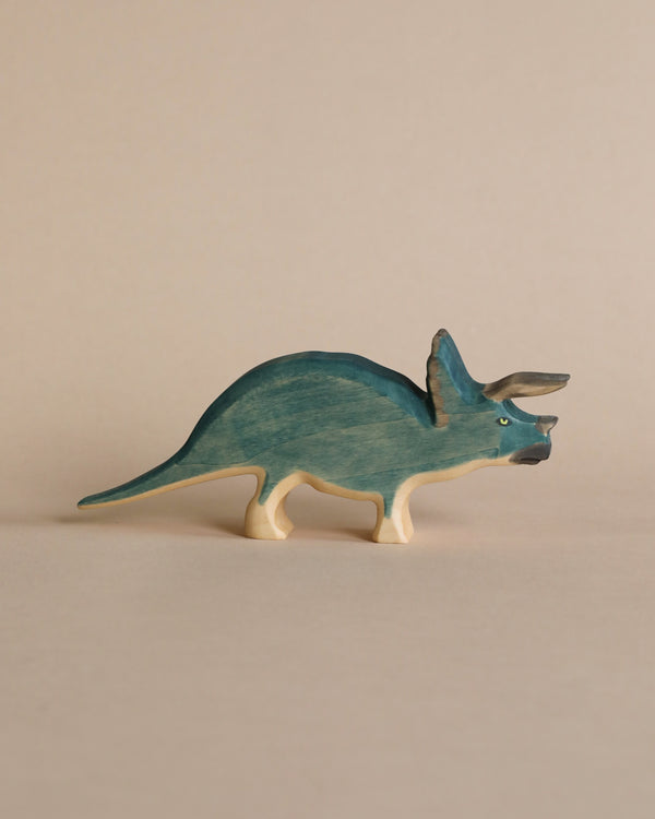 A high-quality Handmade Holzwald Triceratops toy painted in shades of blue and natural wood, standing against a plain beige background.