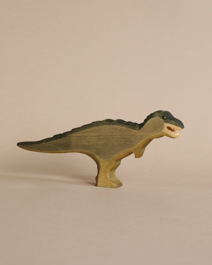 A Handmade Holzwald T-Rex Green, resembling a spinosaurus, painted in green and cream colors, stands against a beige background.