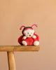 The Bukowski - Ziggy Ladybug plush bear, dressed in a red and black ladybug costume, sits on a wooden stool with a plain beige background.