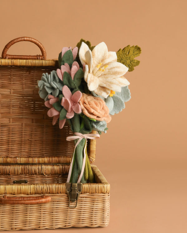 The Handcrafted Felt Flower Bouquet rests against an open wicker basket, displayed on a soft beige background.