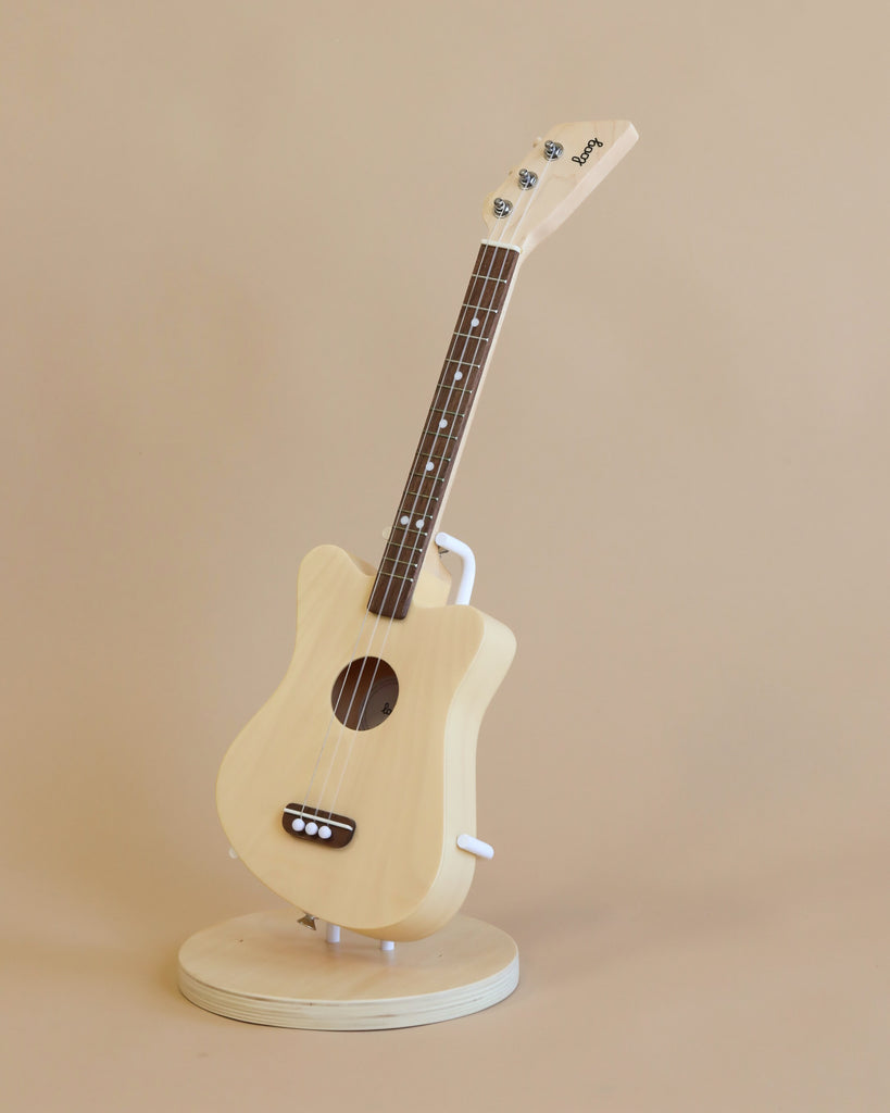 A wooden kid's guitar in natural wood, placed on a stand.