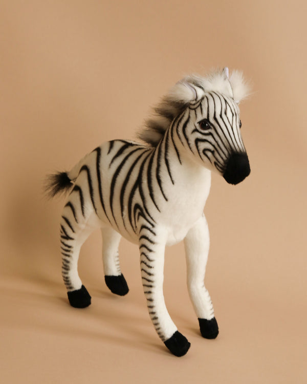 A Baby Zebra Stuffed Animal with detailed black and white stripes and a fluffy mane stands against a warm beige background. Its eyes and nose are lifelike, enhancing its realistic appearance.