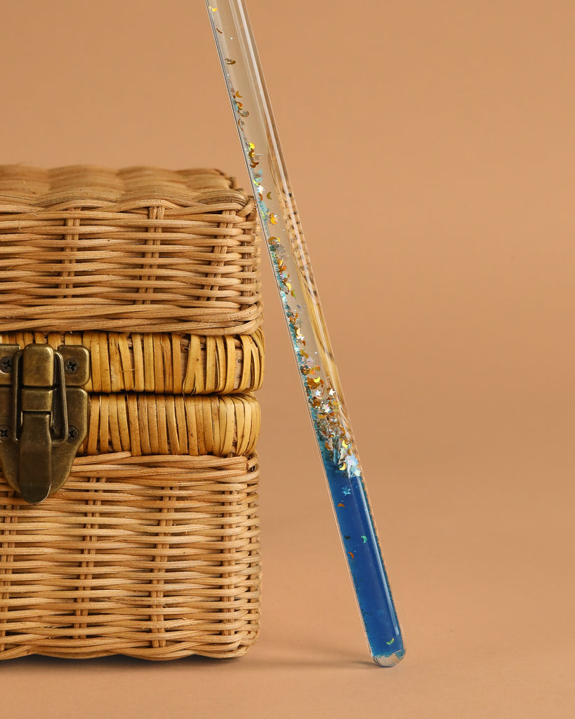 A straw box with a blue liquid features the Konges Sloejd Magical Glitter Wand - Rocket.