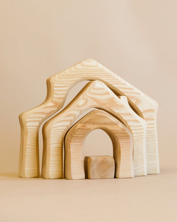 A set of Ostheimer house-shaped wooden toys, made of light-colored wood with natural grain patterns, set against a plain light background.