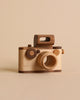 Father's Factory | Vintage Style Wooden Toy Camera with a minimalist design, featuring a large circular lens and small round buttons on a plain beige background.