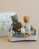 Three plush animal toys—a Maileg Teddy Mum, a cat, and a bunny—sit on a Maileg couch with a patterned gift box behind them on a neutral background.