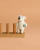 The Finger Puppet: Polar Bear Catching a Fish stands on a wooden rack against a plain beige background, perfect for imaginative play.