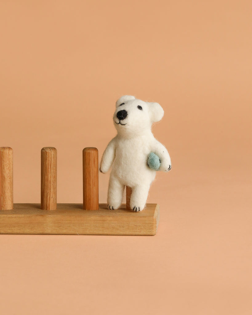 The Finger Puppet: Polar Bear Catching a Fish stands on a wooden rack against a plain beige background, perfect for imaginative play.