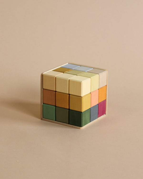 A Raduga Grez | Small Cube Blocks with a mirrored surface and sections in various muted colors, all finished with non-toxic paint, set against a plain, light beige background.