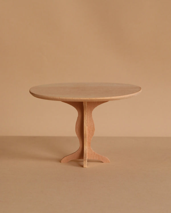 The Maileg Oval Dining Table, Miniature - Bunny/Rabbit Size features a small, round wooden design with a single pedestal base, highlighting fine craftsmanship against a plain beige background.