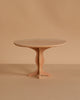 A small, round, wooden table with a simple design stands against a plain beige background. Ideal for showcasing the Maileg Ballet Bunny and Rabbit Set, it features a single central support with curved legs for a charming display.
