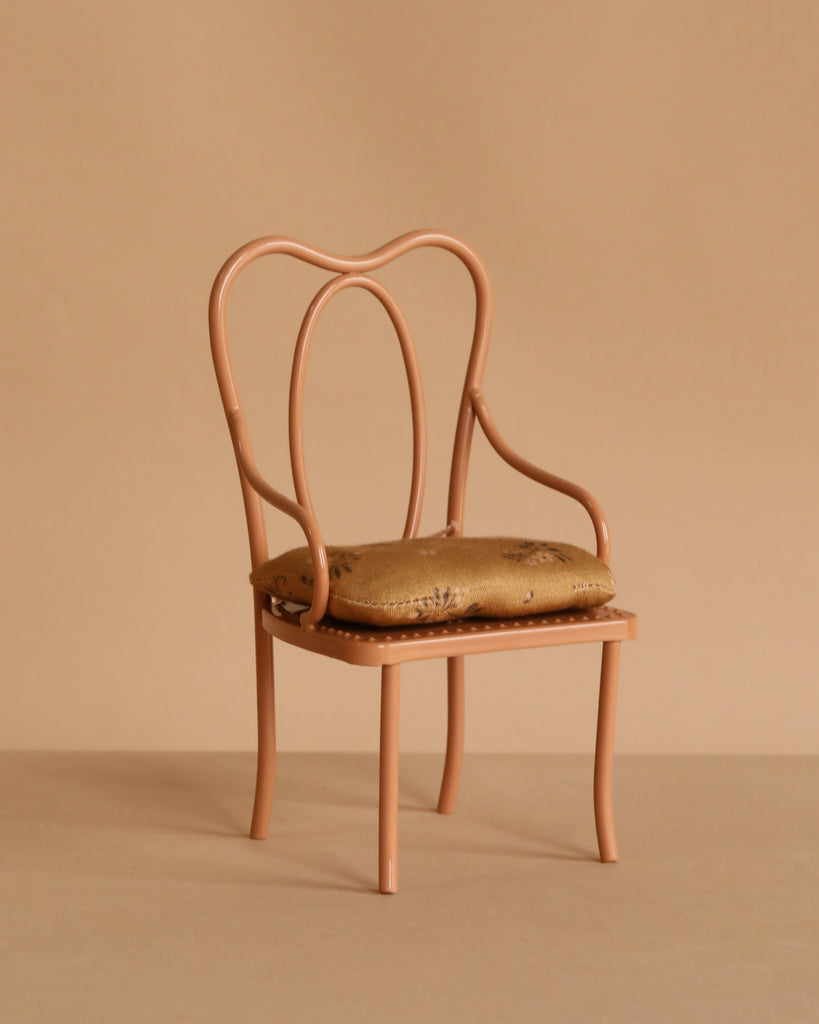 A vintage-style chair with a curved metal frame and patterned cushion sits next to the Maileg Ballet Bunny and Rabbit Set, both displayed against a plain beige background.