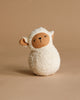 The Organic Cotton Sheep Tumbler features a soft, white textured body, beige face, and floppy ears. Sitting upright on a beige background, it's ideal for sensory exploration and developing gross motor skills.