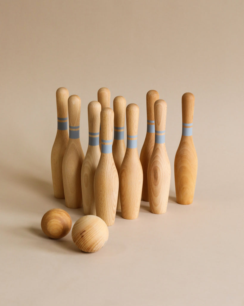 10 wooden bowling pins with light blue stripes painted on them and 2 wooden bowling balls.