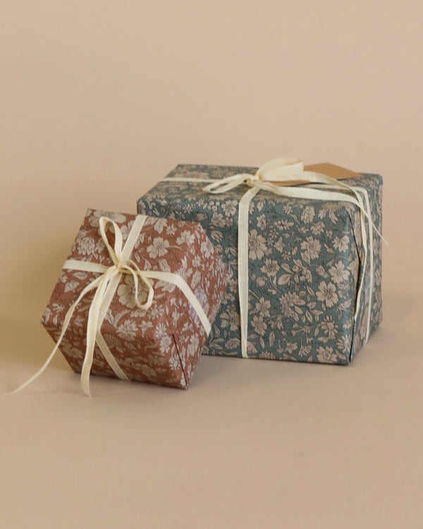 two boxes gift wrapped in floral print wrapping paper, one in blue and one in pink.