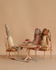 The Maileg Ballet Bunny and Rabbit Set features three dolls in pastel dresses seated around an oval dining table with miniature cakes on vintage-style chairs, set against a beige background for a soft, whimsical effect.