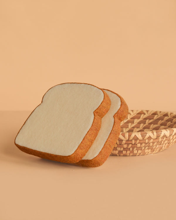 The Bread and Basket Set features two felt toast slices displayed in front of an empty woven basket on a beige background, ideal for play food or a felt breakfast set.