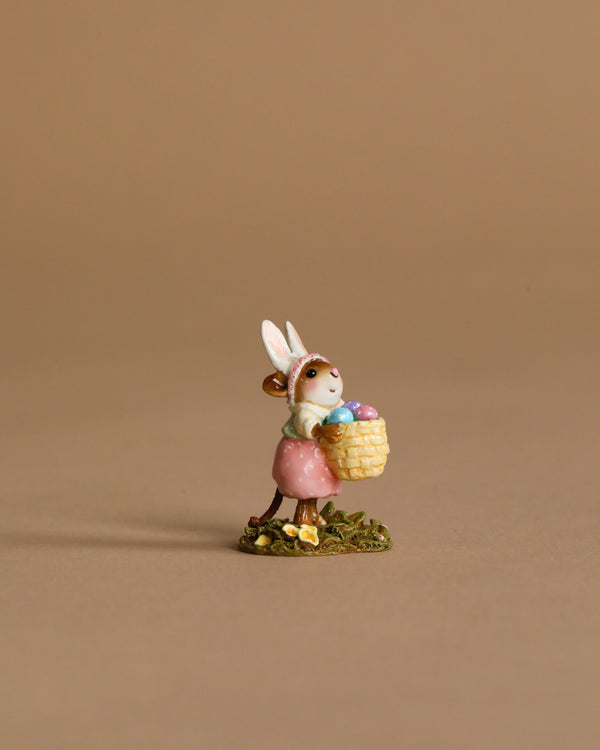 The Wee Forest Folk Tiny Collectible - Hoppy Easter Girl features a hand-sculpted mouse with bunny ears and a pink skirt, holding a basket of colorful eggs on grass against a plain beige background.