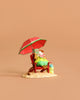 The Wee Forest Folk Tiny Collectible - Perfect Beach Day! features a hand sculpted mouse lounging on a red beach chair under an umbrella, reading with a drink on the sand, set against a plain light brown background.