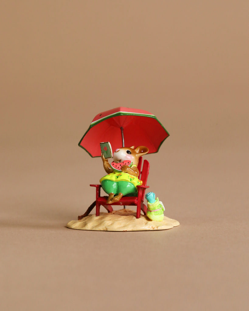 The Wee Forest Folk Tiny Collectible - Perfect Beach Day! features a hand-sculpted mouse in green shorts relaxing on a red chair under a matching umbrella, holding watermelon and a book, with tiny accessories on sandy ground.