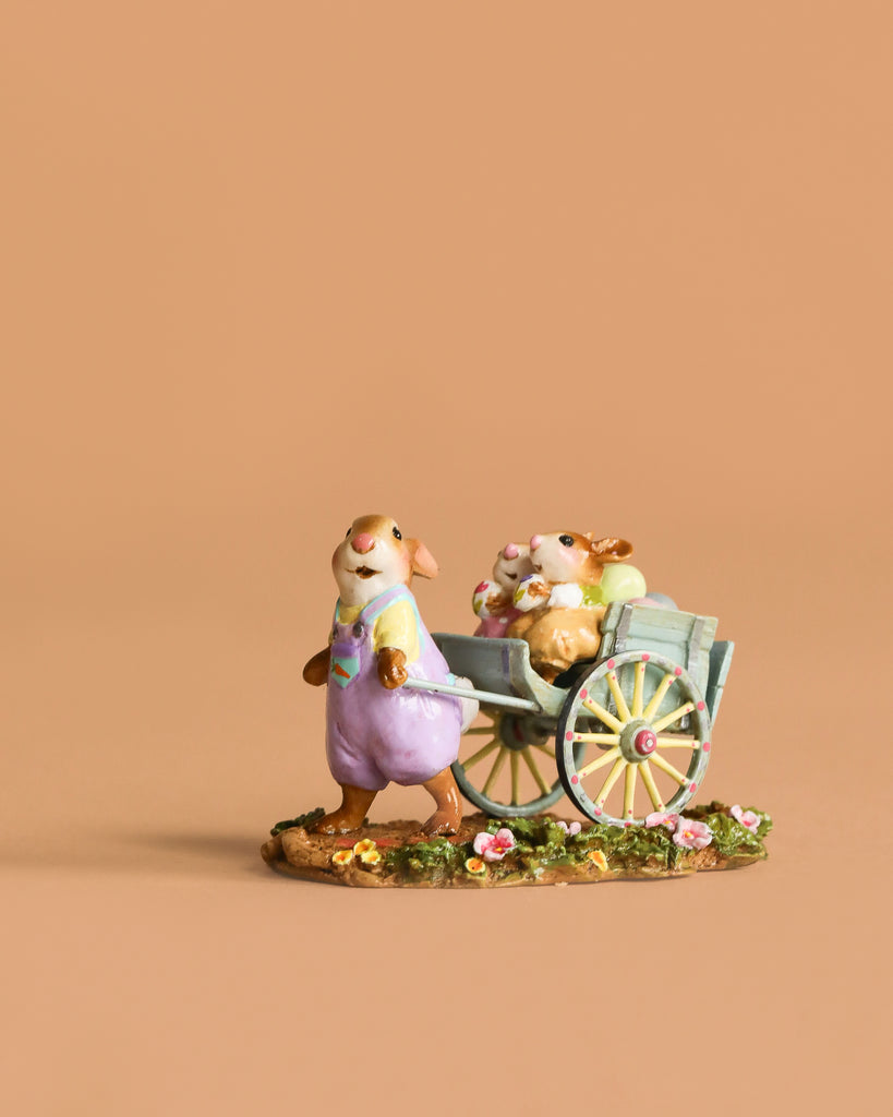 The Wee Forest Folk Tiny Collectible - Easter's on its Way features a hand-sculpted mouse in overalls pulling a cart with two baby mice on a flower-adorned base, perfect for collectors. Not a toy.