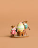 The Wee Forest Folk Tiny Collectible, "Colossal Easter Coloring," features two mouse figurines—a pink-dressed mouse beside a large, colorful Easter egg and another climbing a ladder to paint it—all set against a plain tan background.