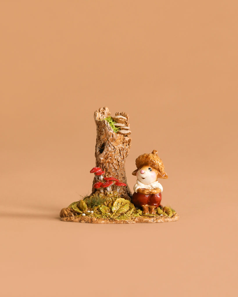 Wee Forest Folk Tiny Collectible - My Happy Place: A small, hand-sculpted gnome with a straw hat sits by a tree stump and red mushrooms on grass, set against a beige background.