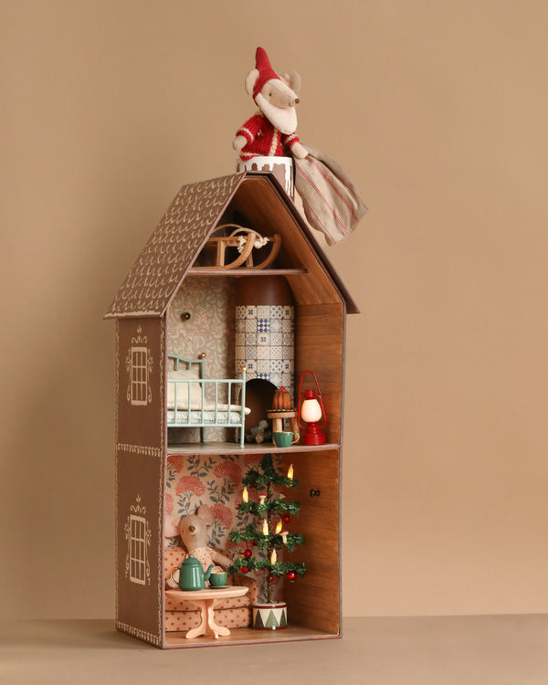 The Maileg Gingerbread House Christmas Set features a mouse in a red outfit atop the house, another by the Christmas Tree inside, plus miniature furniture and festive décor filling every cozy room.