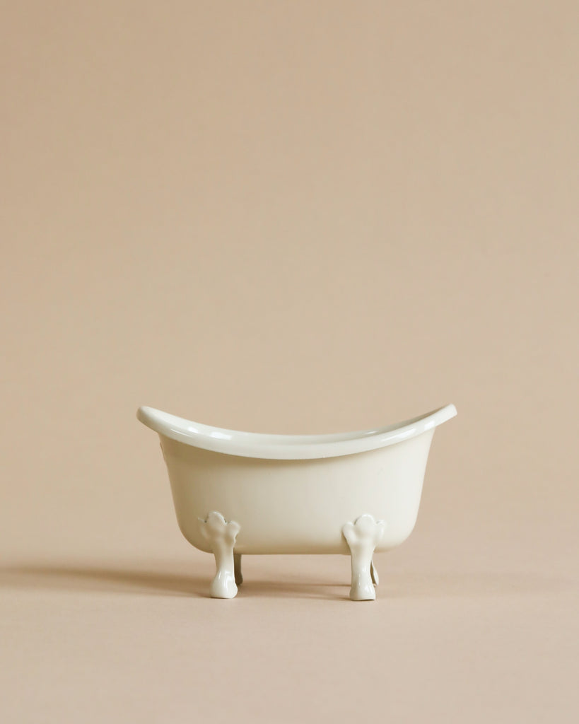 The Maileg Bonus Room Bathroom Set features a small, white, vintage-style clawfoot tub on a beige surface with a matching background—ideal for miniature dollhouse decor or completing your Maileg bathroom scene.