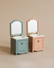 Two Maileg Miniature Sinks With Mirrors in soft blue and pastel pink colors against a neutral background, each featuring a drawer and golden faucet details. These units are designed to fit perfectly into a Ma