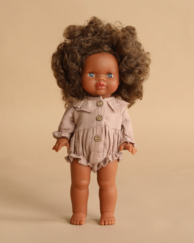 The Minikane Standing Doll (14") – Charlie with Clothing features a brown-skinned, anatomically correct doll with curly brown hair in a beige romper with large buttons, shown standing upright against a plain beige background.