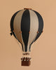 The Hot Air Balloon - Black features handmade black and beige panels, a small brown basket, and white ropes—perfect as a charming children’s room decoration against a neutral background.