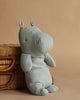 The Maileg Hippo, Medium - Blue Grey, from the Safari Friends collection, with small ears, rests gently against a woven wicker basket on a beige background.
