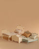 The Maileg Vintage Bed, Mouse Size - Off White, features a charming vintage-style frame and patterned bedding, perfect for dollhouse displays. Shown arranged on a beige surface with coordinating background for added appeal.