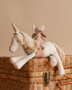 A Maileg Unicorn with a silver horn and yellow mane, adorned with a small toy mouse riding on its back, is placed atop a cotton and linen wicker chest against a beige background.