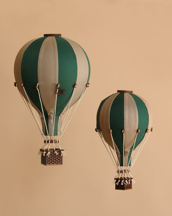 Two Hot Air Balloon - Light Brown / Green decor pieces with brown baskets float against a beige backdrop—perfect vintage-style accents for a charming children's room.
