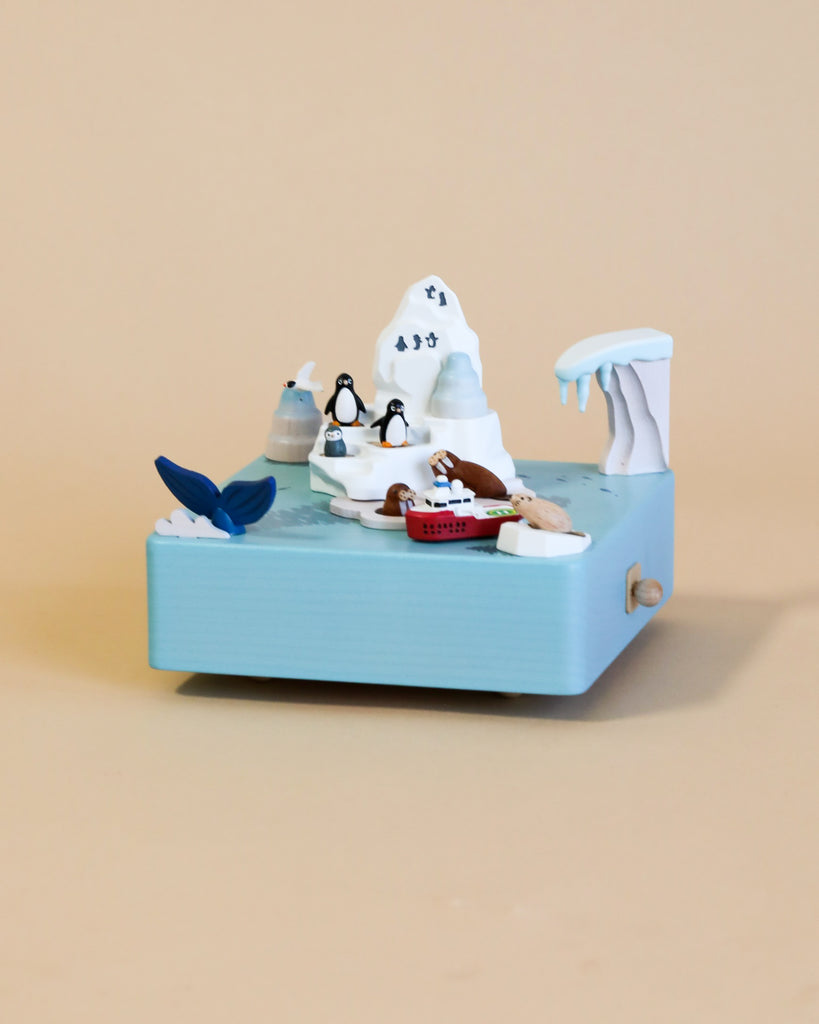 A Wooden Antarctica Music Box from Wooderful Life, featuring a polar bear with sunglasses, a fish tail, penguin, and other small details crafted from sustainably sourced wood, set against a miniature beach scene diorama.