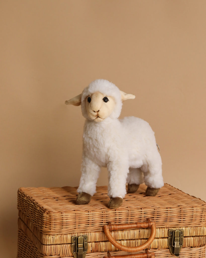 A Lamb stuffed animal, crafted from high-quality man-made materials, standing on a woven wicker suitcase against a soft beige background. The lamb toy is fluffy with an expressive face and large, soft ears.